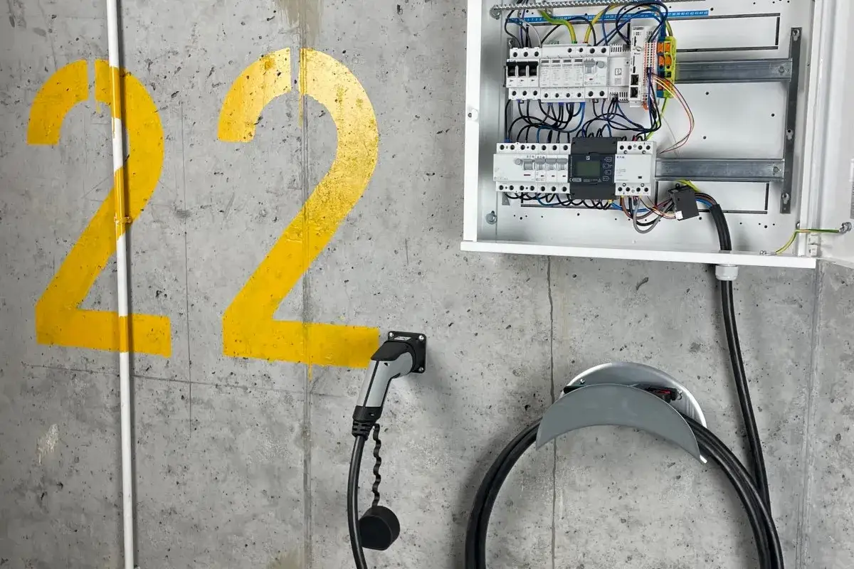 Rodzina ładująca samochód elektryczny w garażu wallboxem, uśmiechnięta, nowoczesny dom