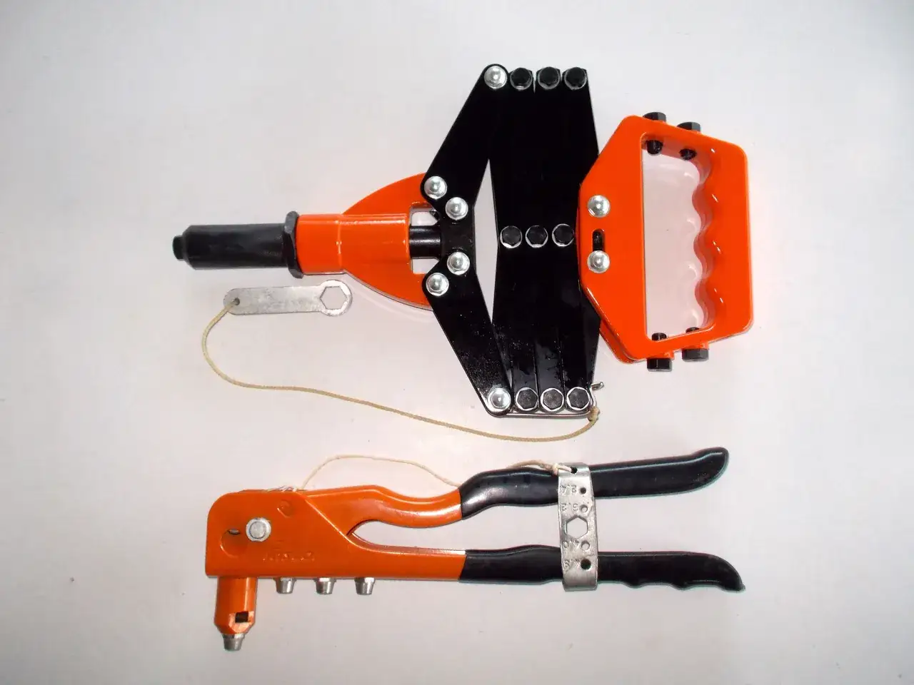 Dos remachadoras, una con mango extensible y otra manual, muestran cómo funciona una remachadora para unir materiales.