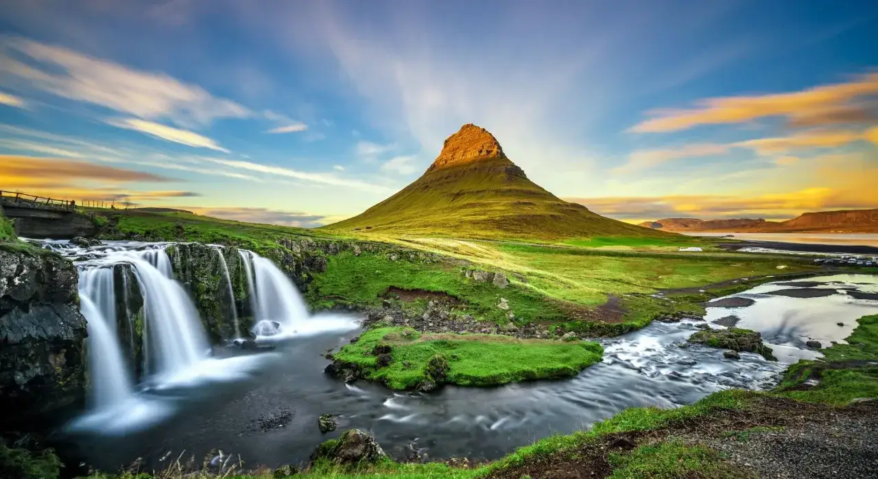 Malowniczy wodospad i g&oacute;ra Kirkjufell na Islandii. Idealne miejsce na wędr&oacute;wkę w wygodnych butach na Islandii.