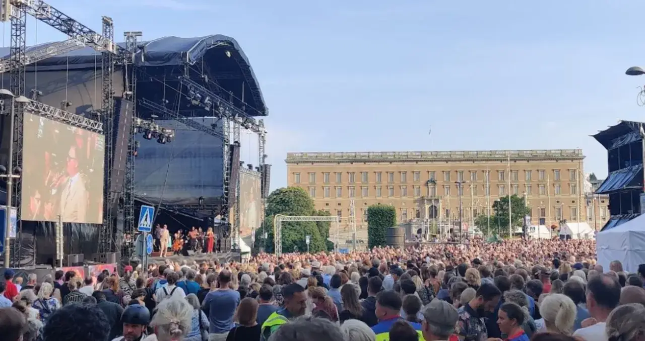 Stor publik vid en utomhuskonsert i Stockholm. En stor scen med skärmar och bakom den syns Kungliga slottet. Stämningen är festlig på sthlm fields.