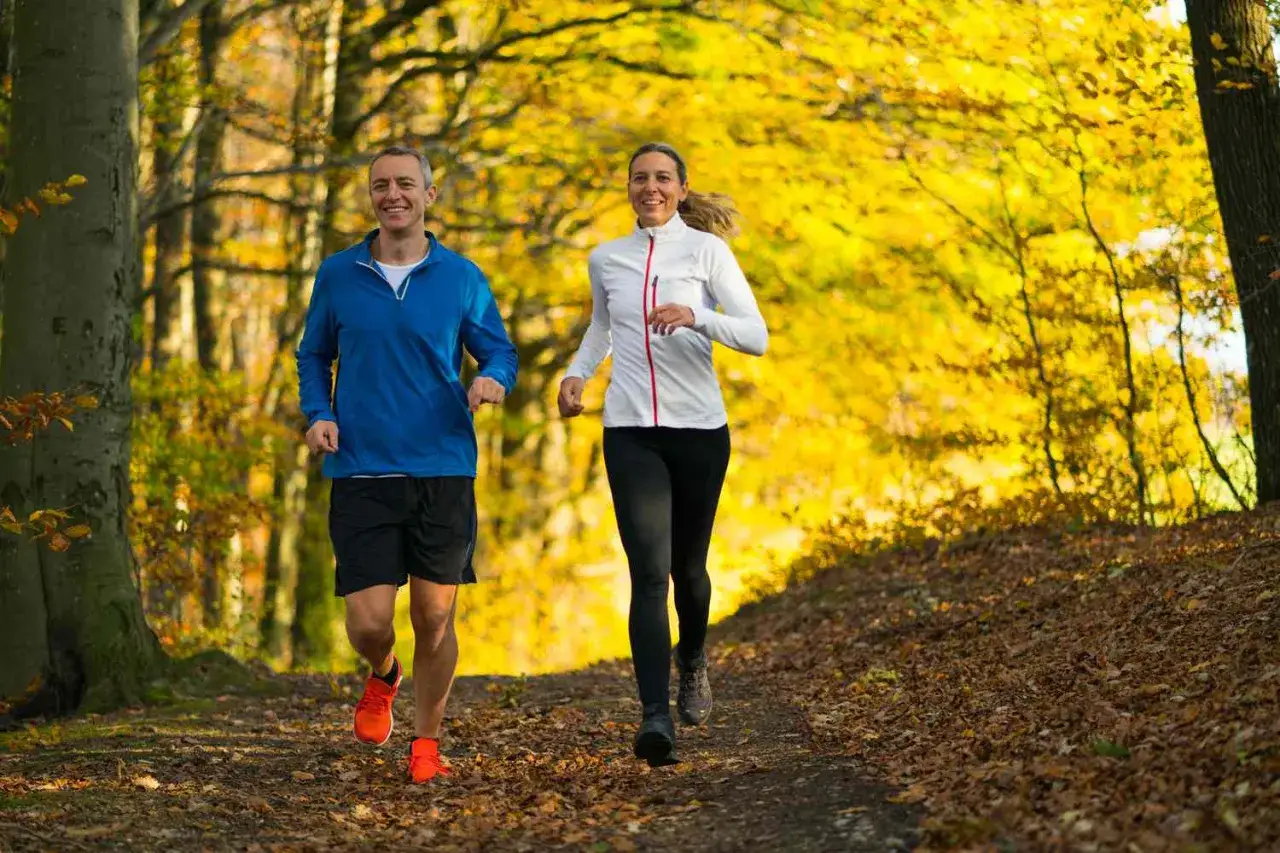 Un couple profite de l'automne pour courir tous les jours dans un parc aux arbres dor&eacute;s.