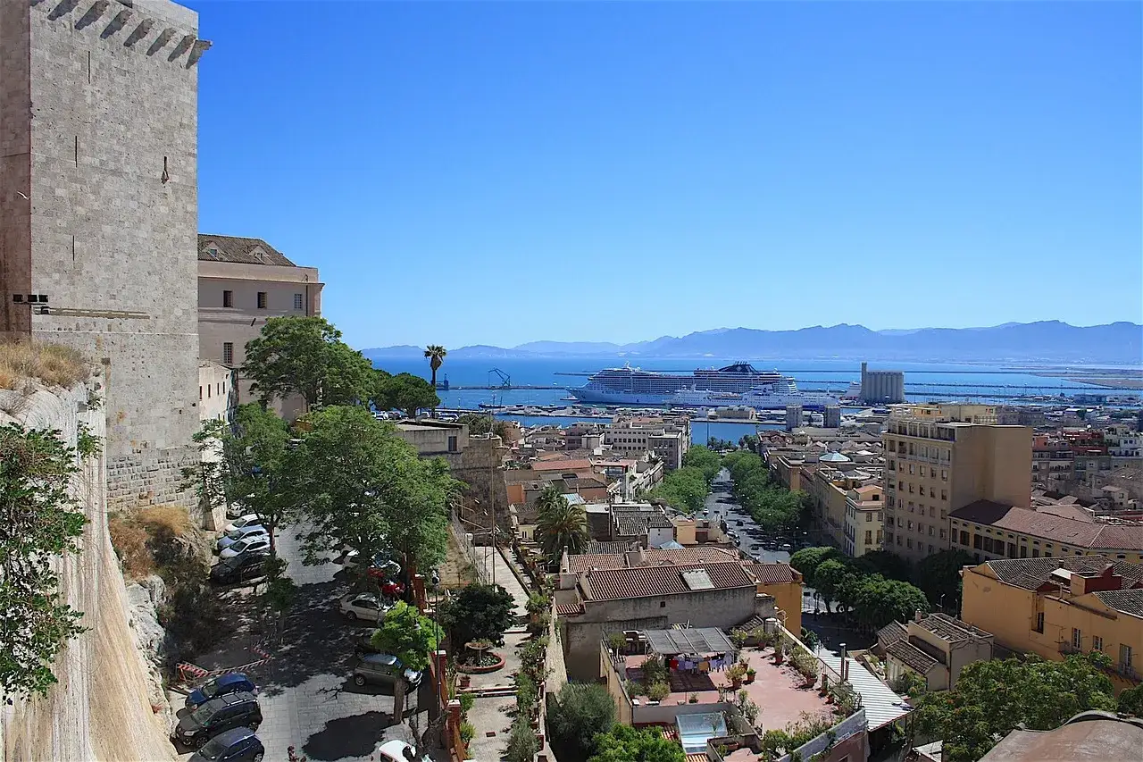 Vista panoramica di Cagliari: castello, porto con navi da crociera e montagne. Ideale per scoprire cosa vedere a Cagliari in un giorno.