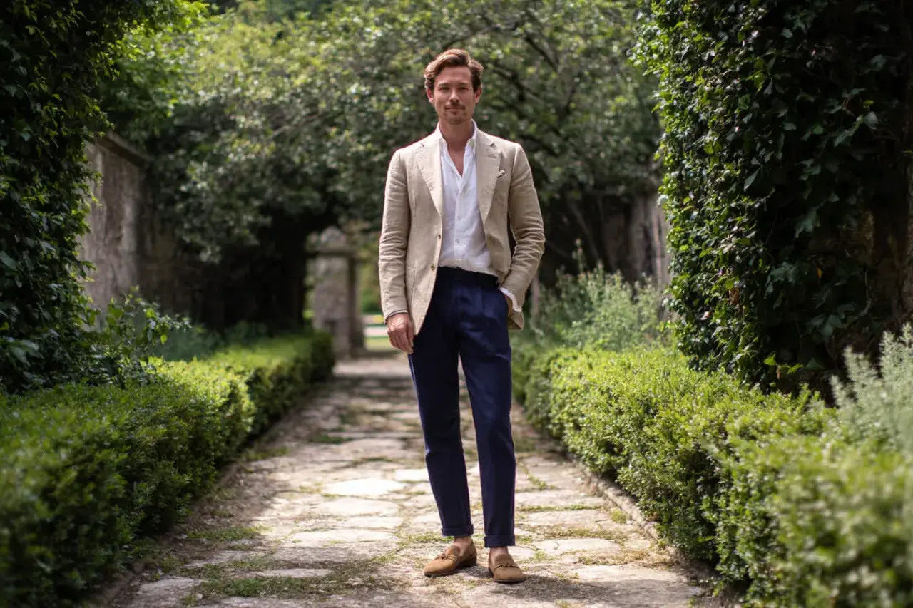 Eleganter Mann in einem hellen Sakko und dunkelblauer Hose, perfekt f&uuml;r ein stilvolles Outfit zur Taufe im Freien.