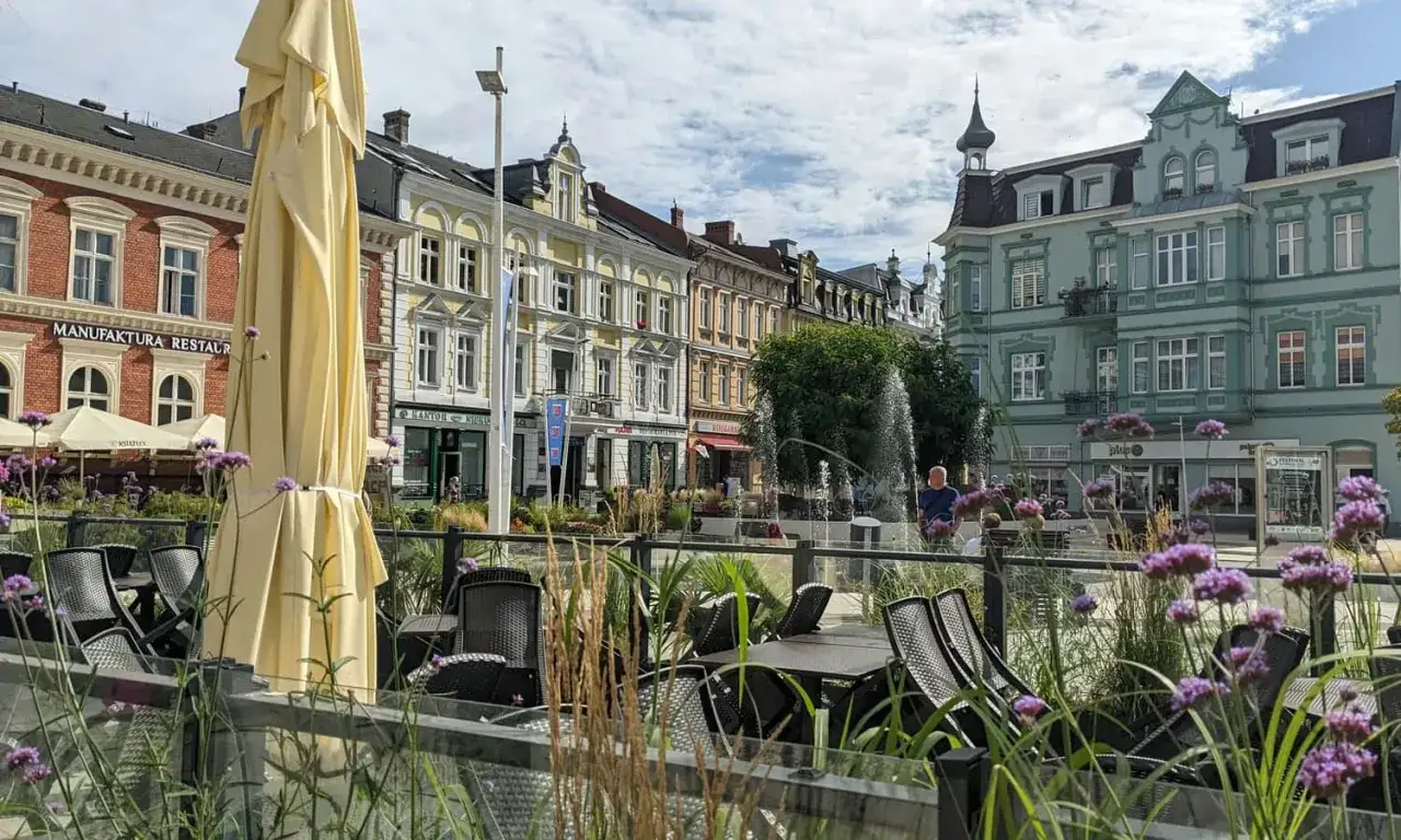 Urokliwe świnoujście stare miasto z kolorowymi kamienicami, fontanną i kawiarnianymi stolikami.