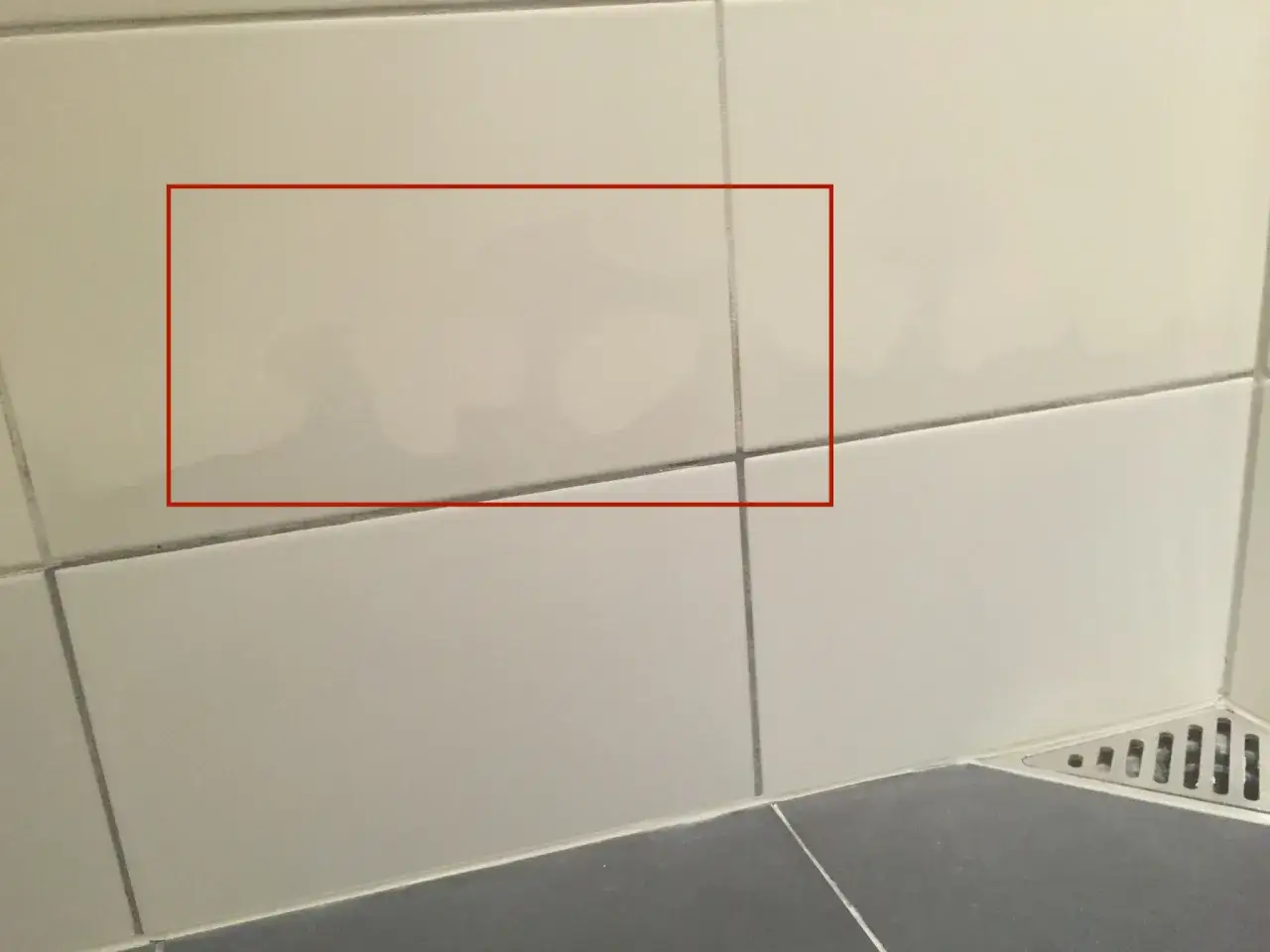Fuktskada kakel syns som mörka fläckar på ljusa väggplattor. Vatten har trängt in.