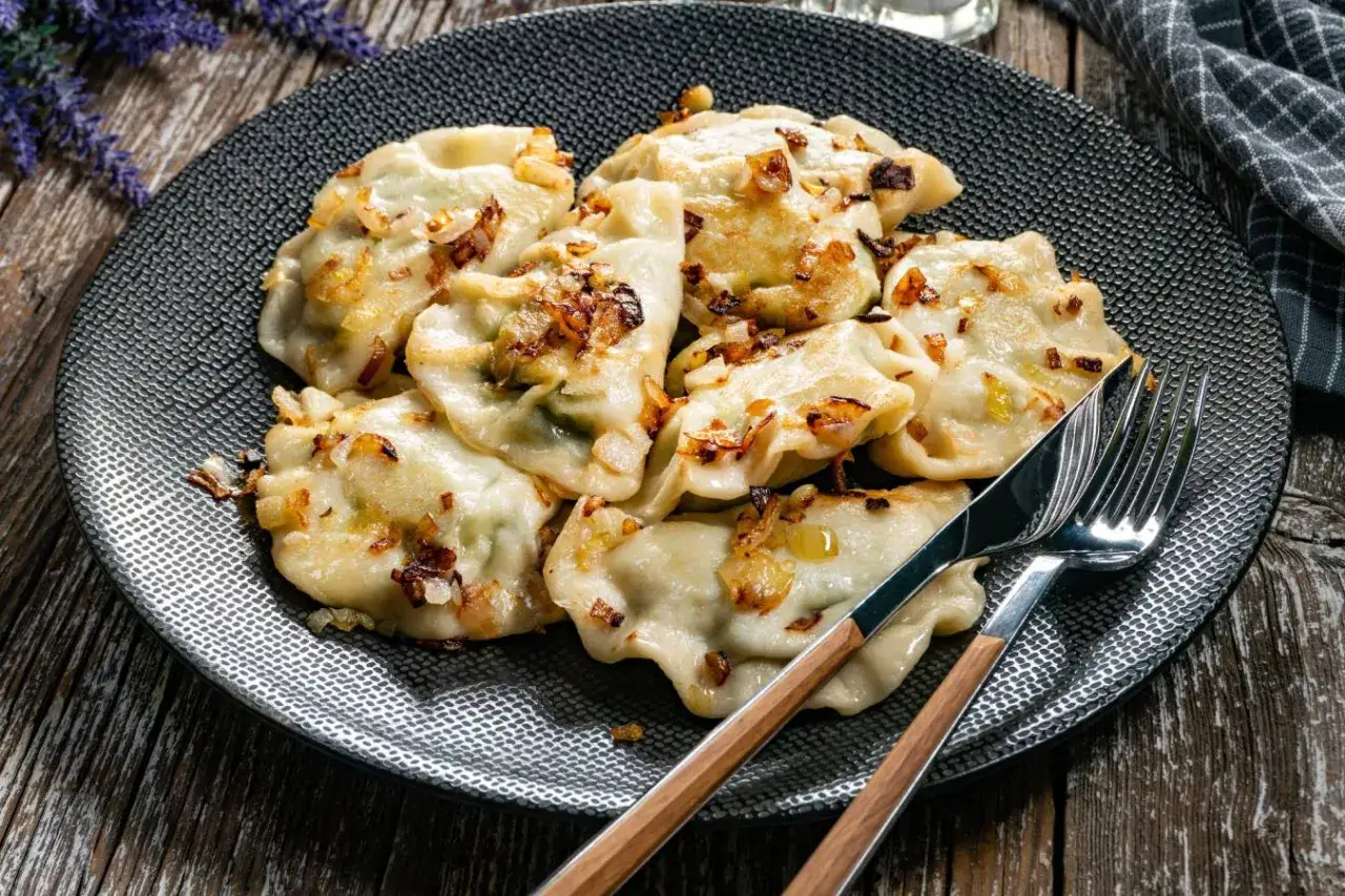 Talerz pysznych pierogów z cebulką. Zastanawiasz się, jak długo gotuje się pierogi? Te wyglądają idealnie!