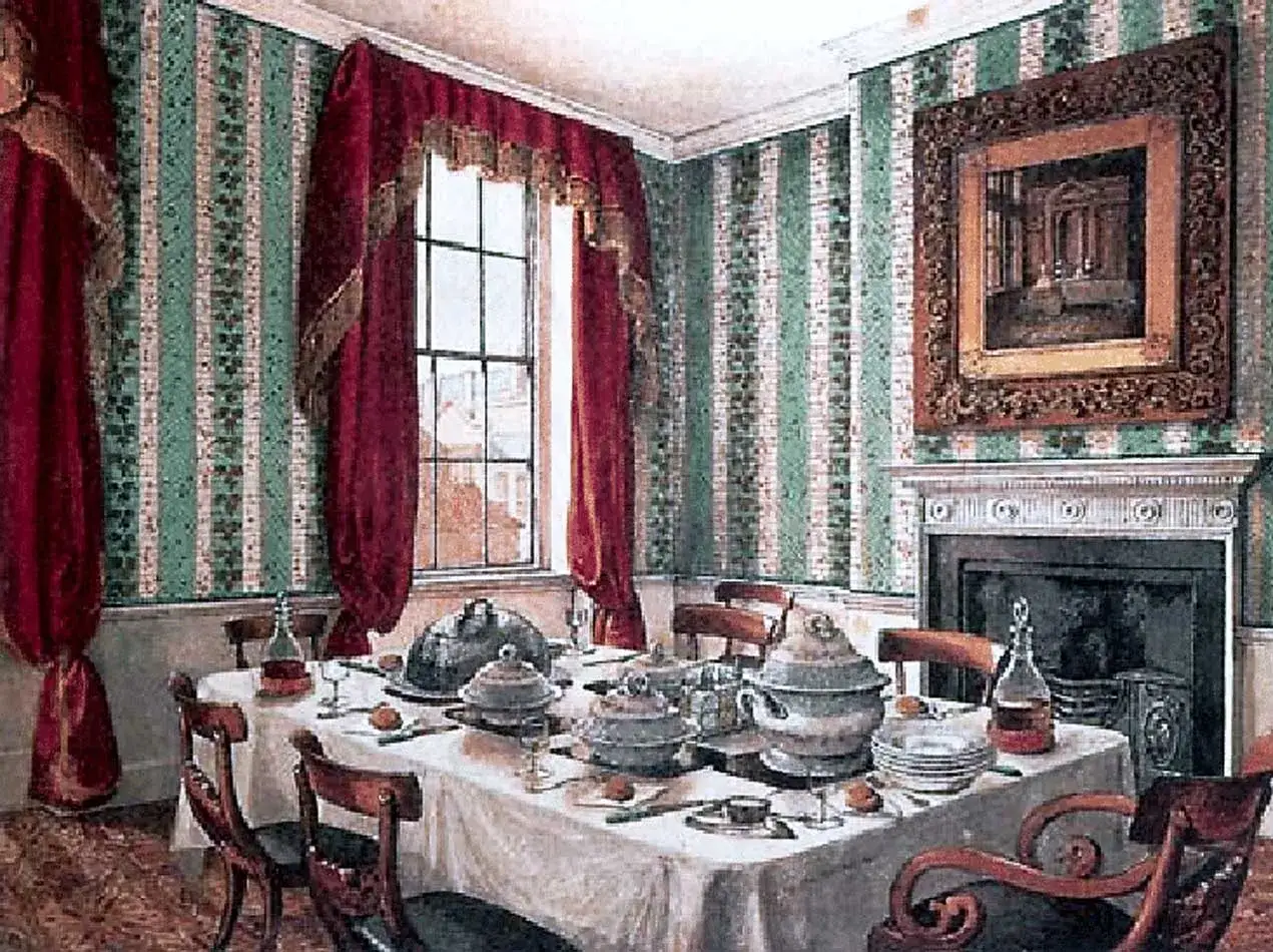 Service plat sur table dressée dans une salle à manger aux murs rayés vert et blanc, avec des rideaux rouges et une cheminée ornée.