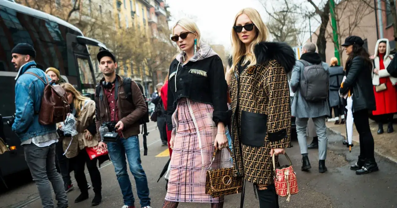 Stylowe kobiety na ulicy, uchwycone w kadrze fotografii modowej. Jedna w płaszczu Fendi, druga w krótkej kurtce i spódnicy w kratę.