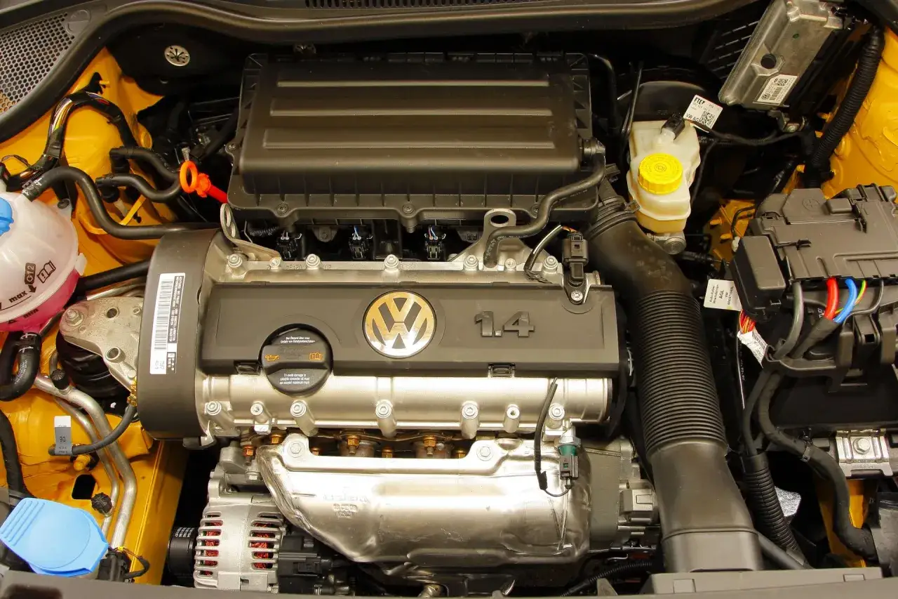 Silnik Volkswagen 1.4 MPI w żółtej komorze silnika, z widocznym logo VW i oznaczeniem pojemności.