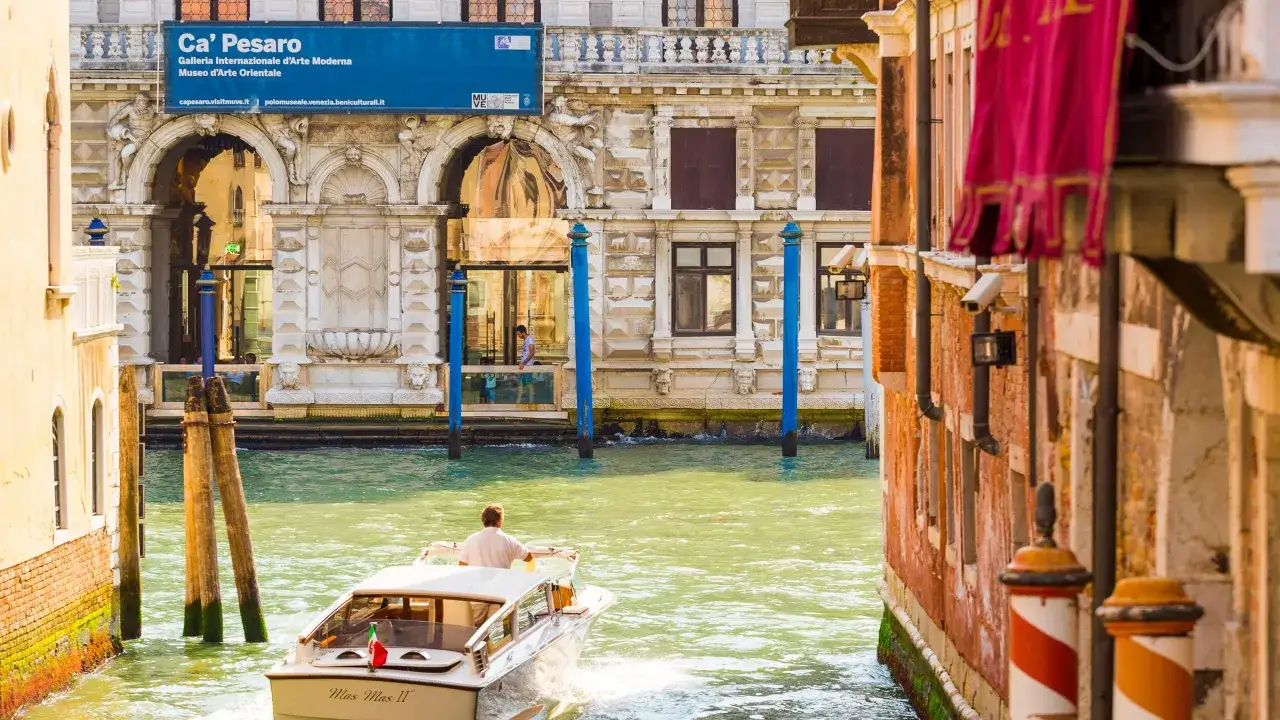 Un bateau navigue sur un canal v&eacute;nitien devant le Ca' Pesaro, mus&eacute;e d'art moderne et d'art oriental.