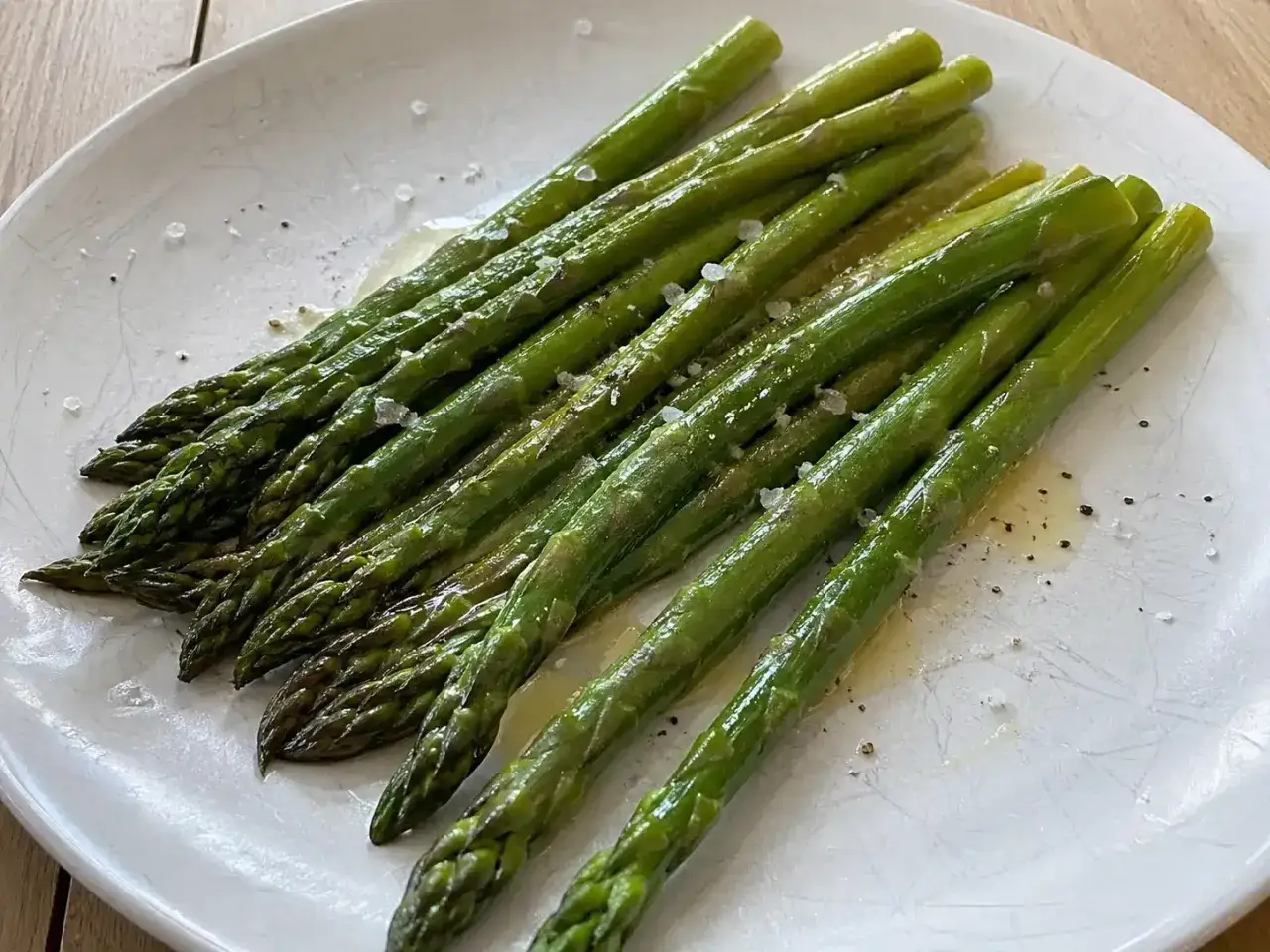 En tallrik med perfekt kokt sparris, l&auml;tt sm&ouml;rad och str&ouml;dd med flingsalt och peppar. En enkel och god r&auml;tt att koka sparris till.