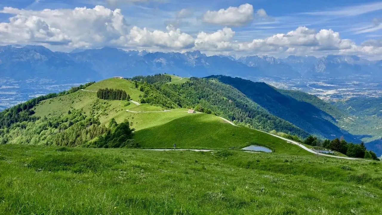 Panorami mozzafiato dalla malga Gardena, con dolci colline verdi, un laghetto alpino e le maestose montagne sullo sfondo.