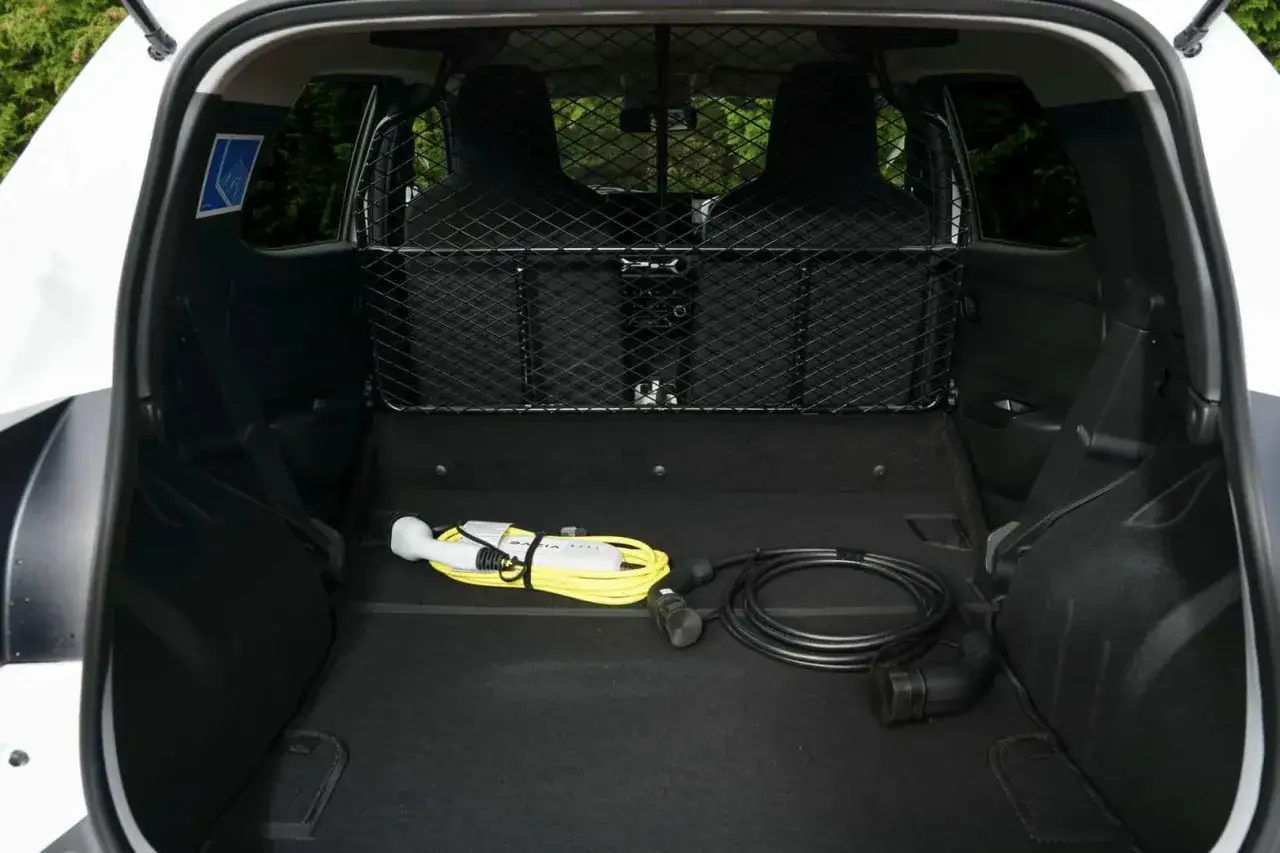 Wnętrze Dacia Spring Cargo z siatką ochronną i kablami do ładowania. Idealny do transportu.
