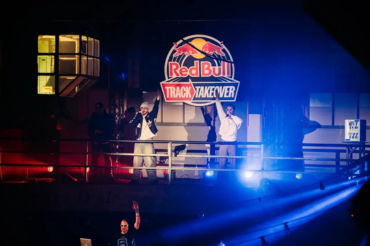 Na scenie Red Bull Track Takeover, młody Igi z mikrofonem, obok niego kolega. W tle logo Red Bull.