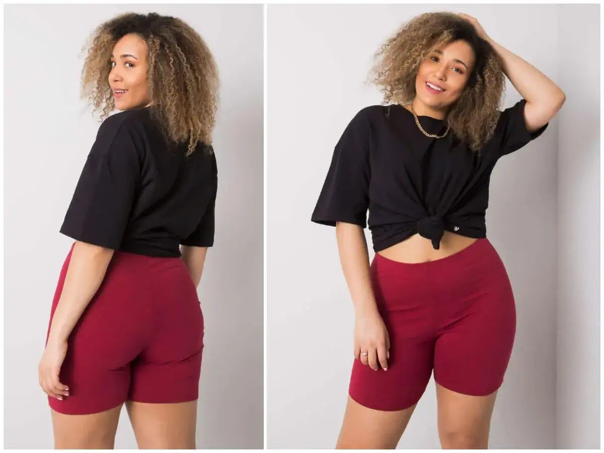 Kobieta plus size w czarnej bluzce i bordowych szortach. Pokazuje, że plus size to piękno w każdym rozmiarze.