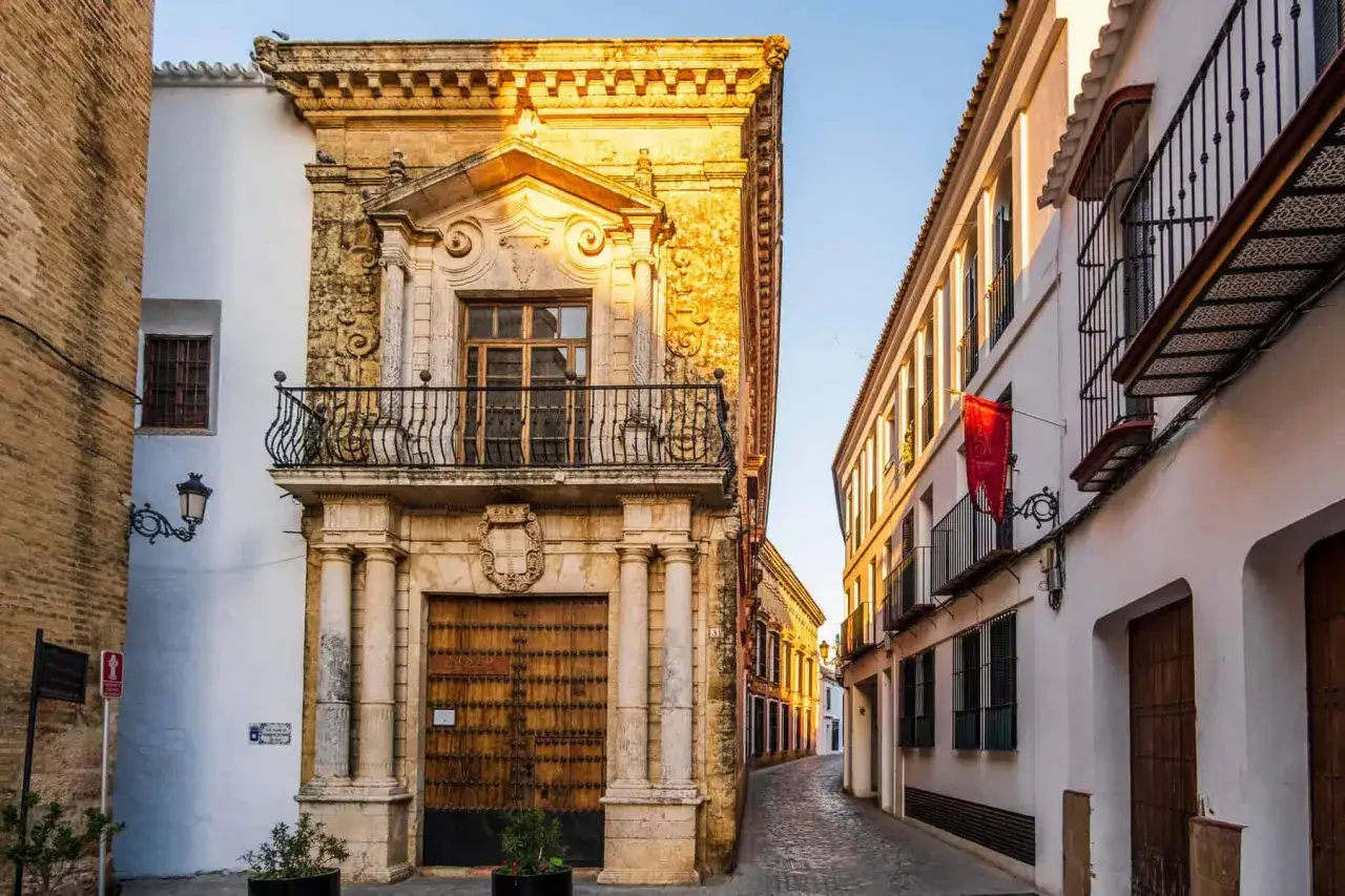 Calle empedrada flanqueada por edificios históricos, un ejemplo de los pueblos bonitos de Sevilla.