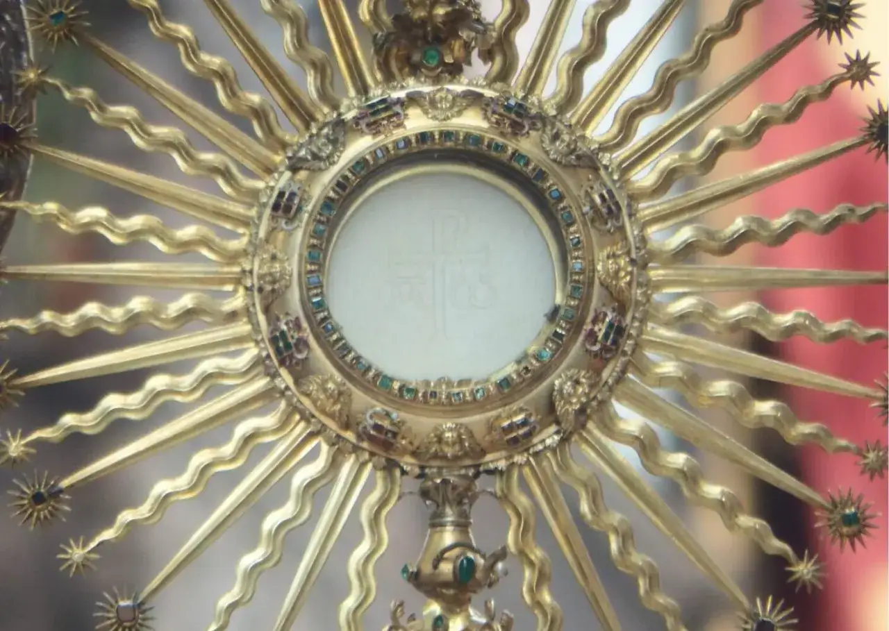 Złota monstrancja z hostią, symbol Najświętszego Sakramentu. Tekst pieśni na wystawienie najświętszego sakramentu towarzyszy tej uroczystej chwili.