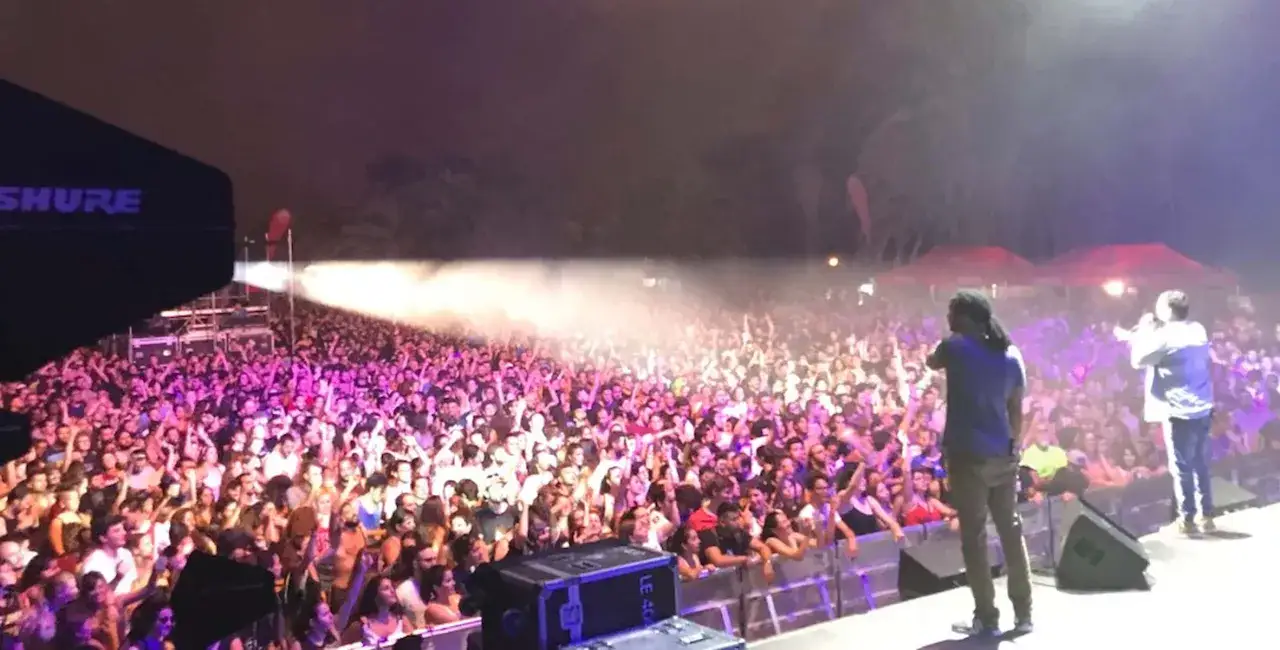 Multitud vibrante en la feria de julio de Valencia, disfrutando de un concierto bajo luces de ne&oacute;n.