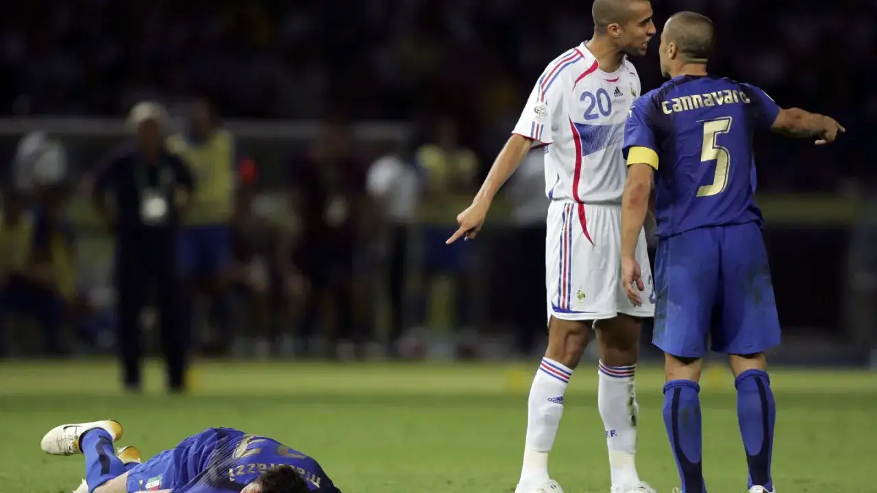 Zidane i Materazzi w gorącej wymianie zdań na boisku. Na dole leży powalony zawodnik.