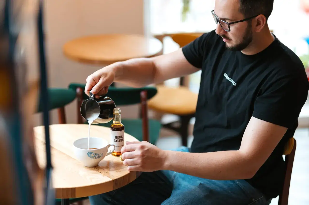 Barista wylewa mleko do kawy. Zastanawiasz się, ile kosztuje kurs na baristę?