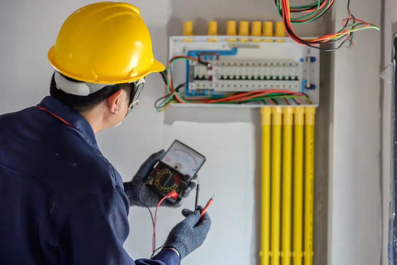 Elektryk w żółtym kasku sprawdza instalację. Zastanawiasz się, ile zarabia elektryk w Norwegii?