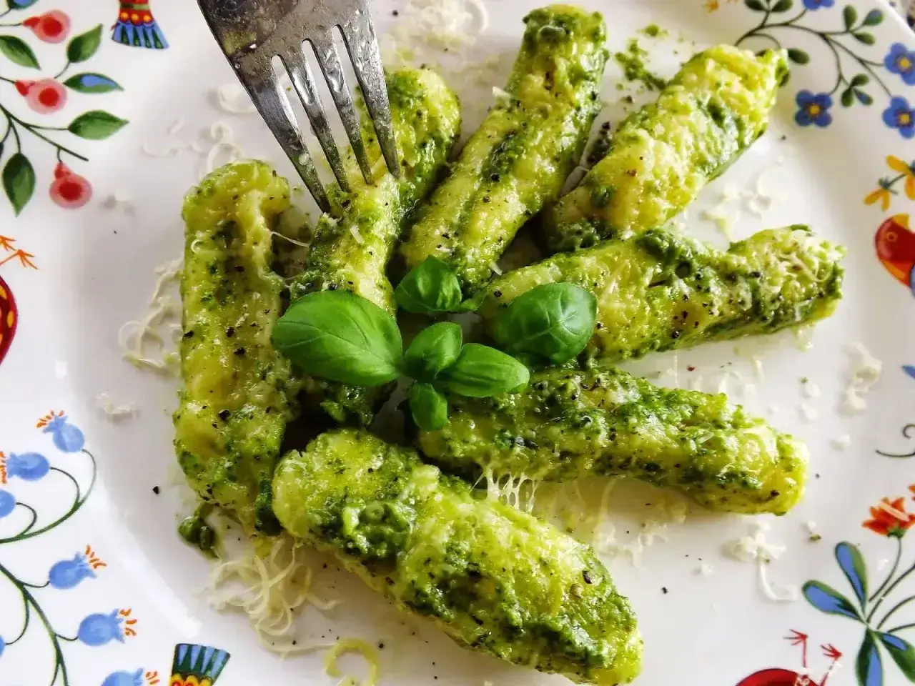 Pyszne gnocchi z zielonym pesto, posypane parmezanem i udekorowane listkami bazylii. Idealne danie dla miłośników włoskich smaków.