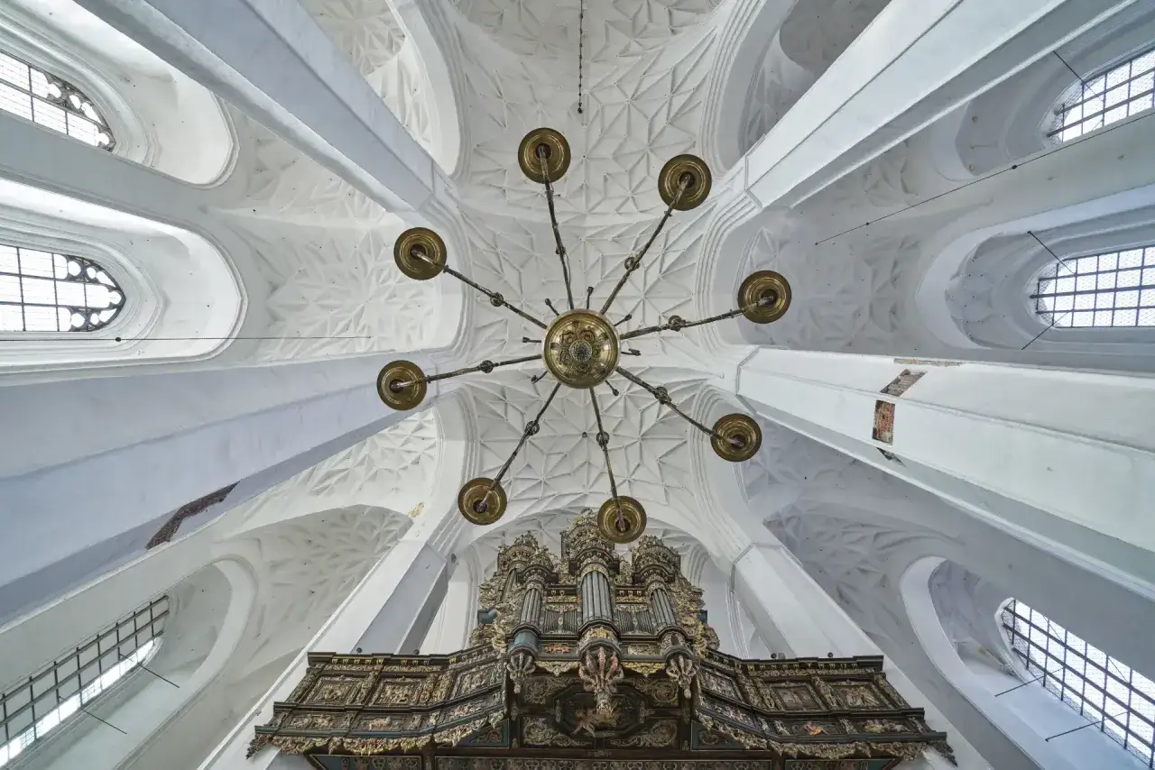 Wnętrze Bazyliki Mariackiej w Gdańsku. Widok na sklepienie, żyrandol i organy. Ciekawostki architektoniczne zachwycają.