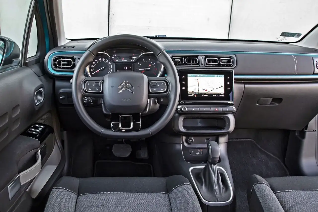 Wnętrze Citroena C3, które często pojawia się w **citroen c3 opinie**. Widoczny ekran multimediów, kierownica i dźwignia zmiany biegów.