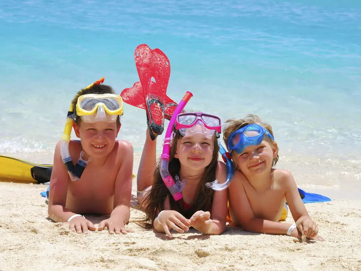 Niños felices con equipo de snorkel en la playa, ideal para saber donde ir de vacaciones con niños.