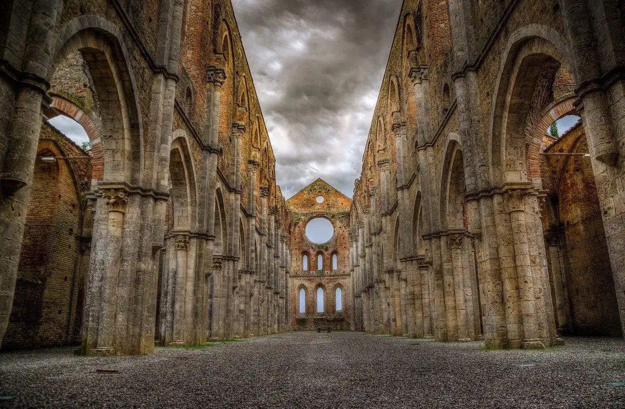 L'imponente **abbazia nel querceto**, con le sue arcate maestose e il tetto mancante, si staglia contro un cielo tempestoso, evocando un senso di storia e mistero.