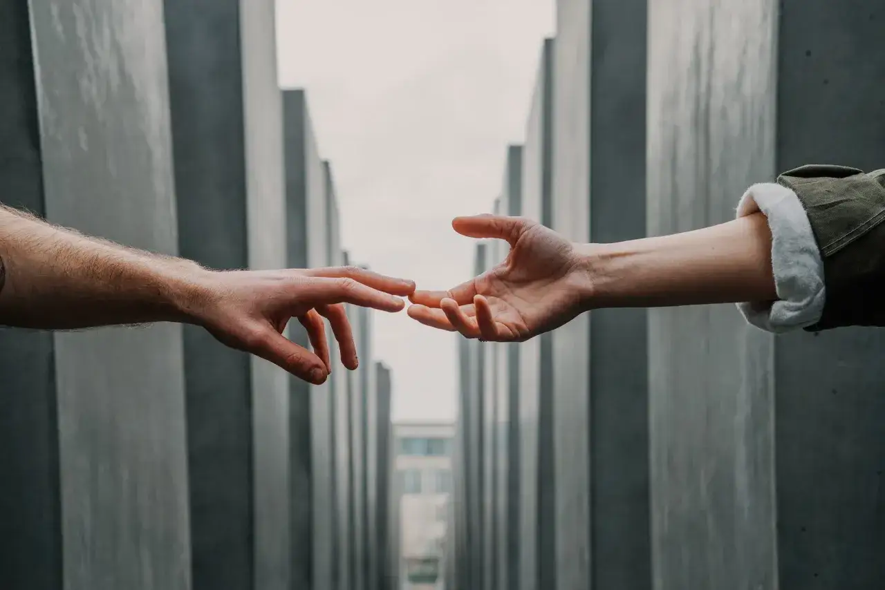 Dwie dłonie prawie się dotykają, symbolizując trudne rozstanie z narkomanem.