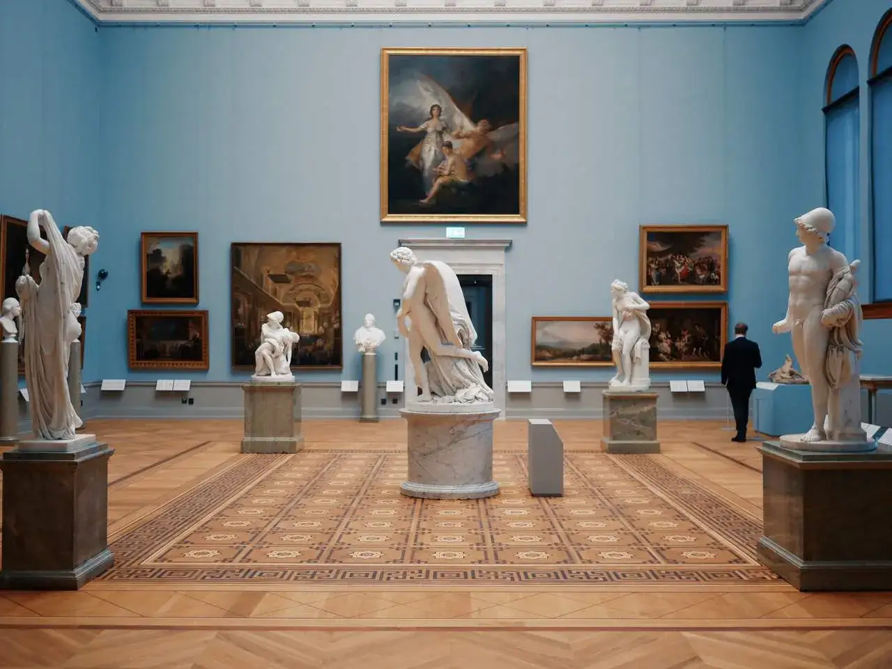 Konsthall med skulpturer och målningar, en man i kostym betraktar verken. En känsla av lugn och skönhet, som på Waldemarsudde.
