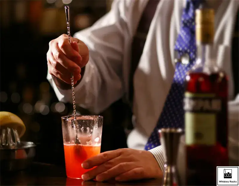 barman profesjonalnie degustujący koktajl z łyżeczki barmańskiej
