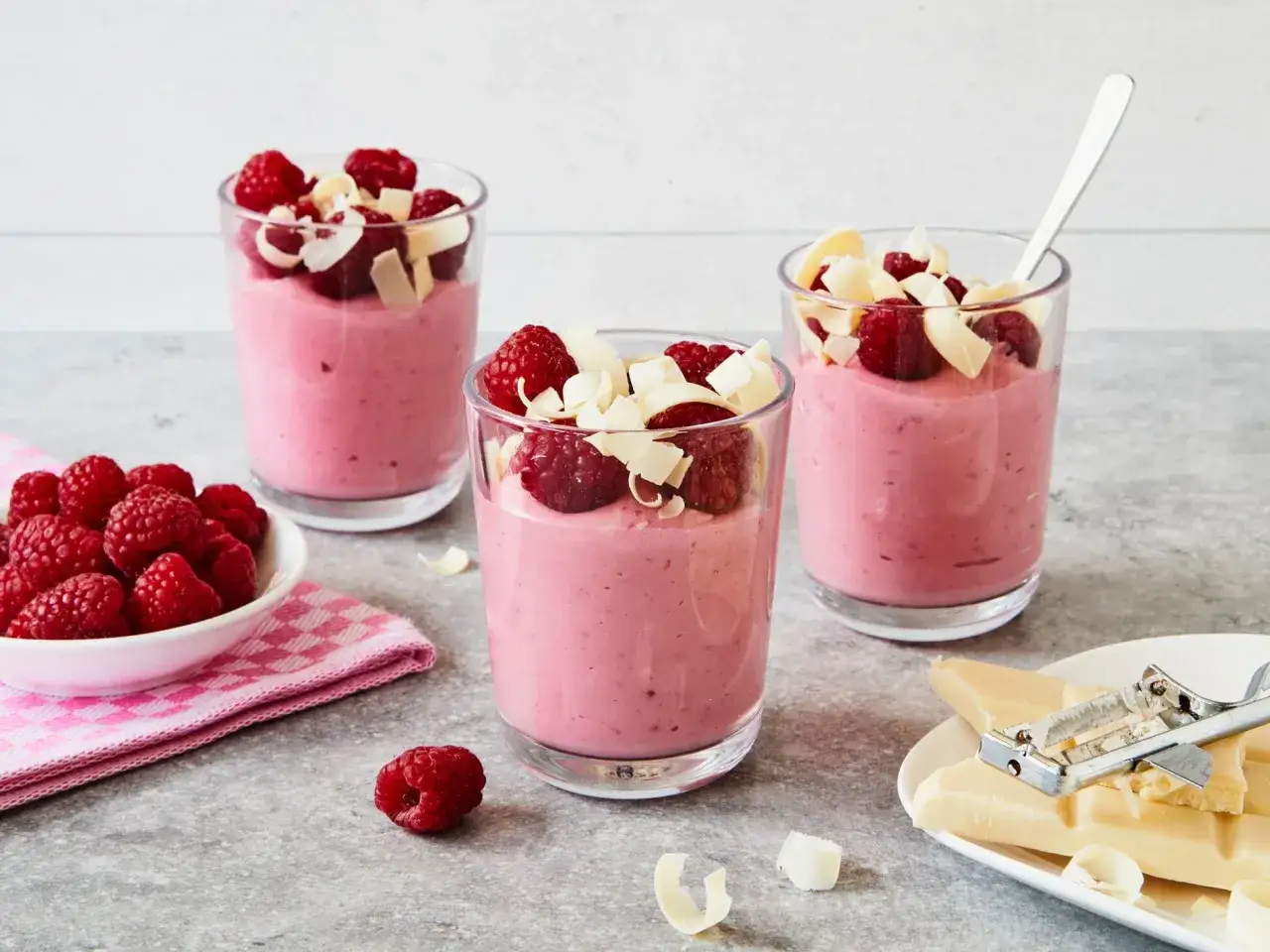 Himbeermousse mit weißer Schokolade, zubereitet im Thermomix, garniert mit frischen Himbeeren und Schokospänen.