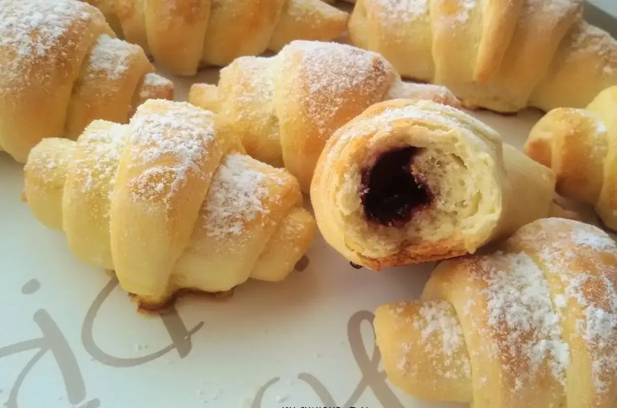 Pyszne, domowe rogaliki z dżemem, posypane cukrem pudrem. Idealne na śniadanie lub deser. Ten przepis na rogaliki jest prosty i szybki.