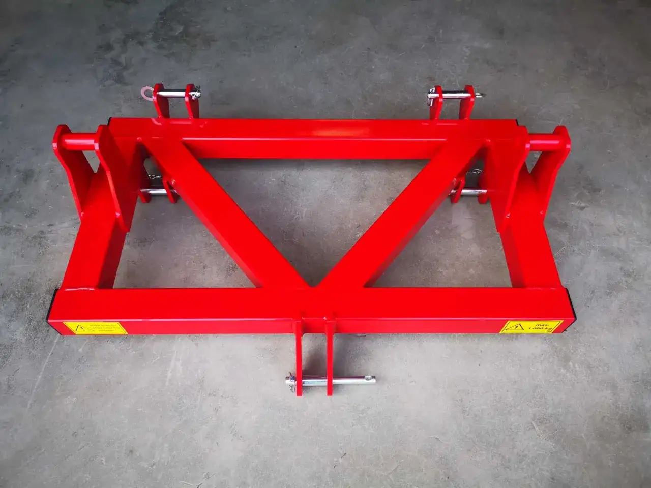 Roter Dreipunktadapter mit stabilen Stahlstreben und Sicherungspins, bereit f&uuml;r den Einsatz auf dem Feld.