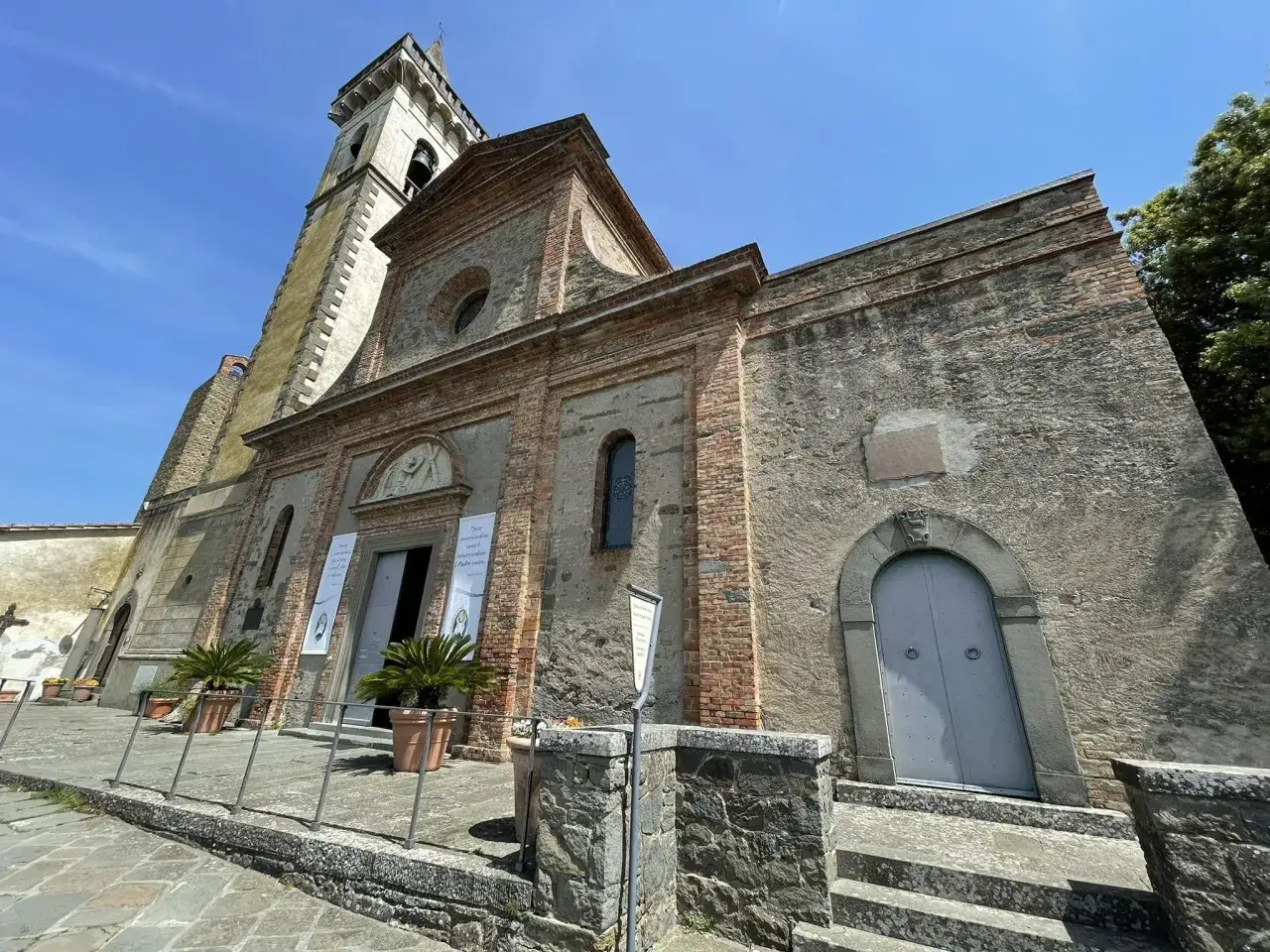 La pieve a Nievole, con la sua torre campanaria e la facciata in pietra e mattoni, si staglia sotto un cielo azzurro.