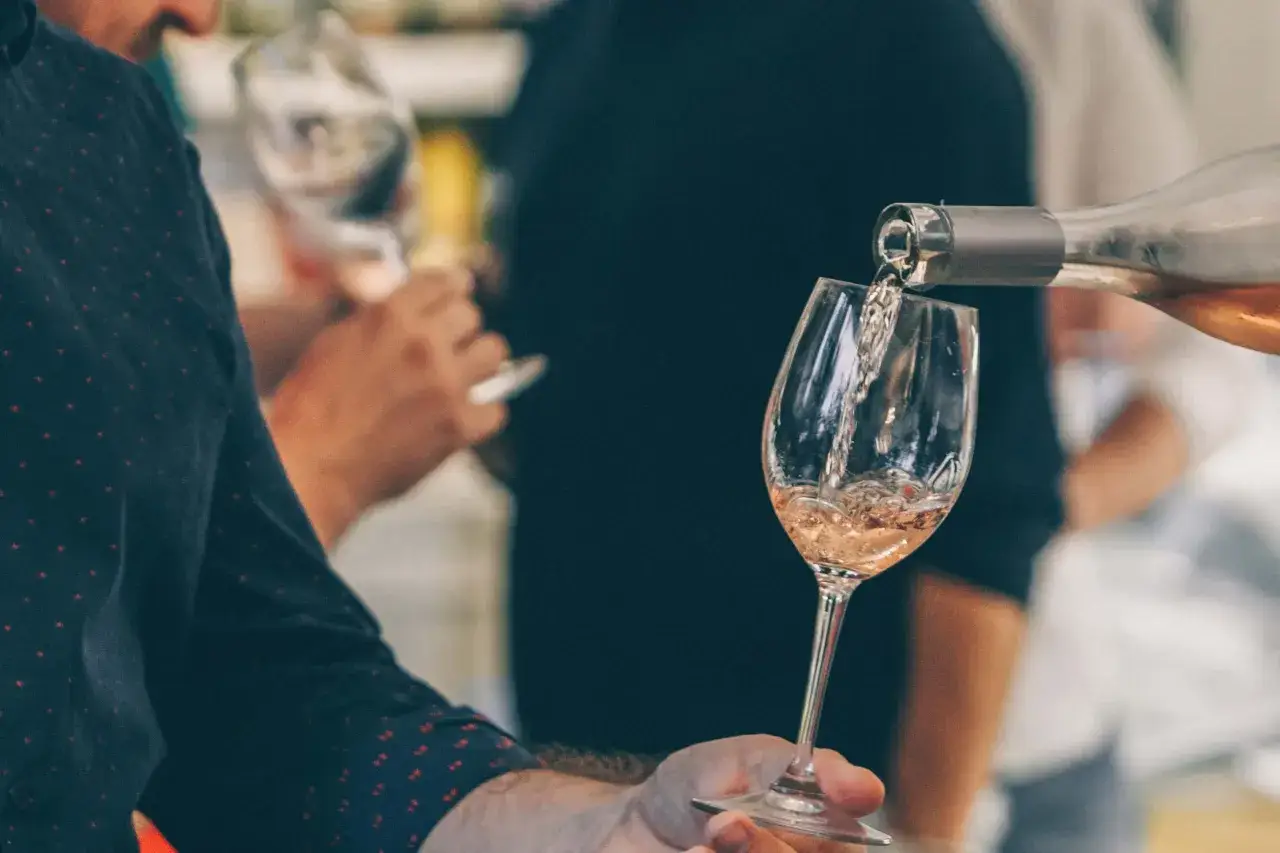 Ein feinherber Wein wird in ein Glas gegossen. Die roséfarbene Flüssigkeit schimmert im Licht.