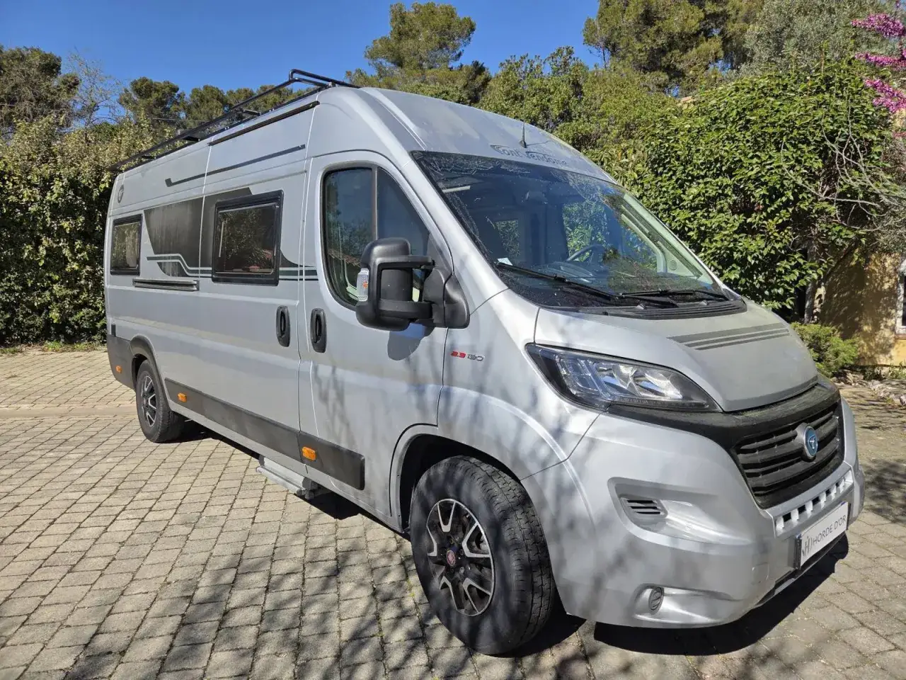 Camping-car Pilote gris, prêt pour l'aventure. Sa fiche technique promet confort et liberté pour vos escapades.