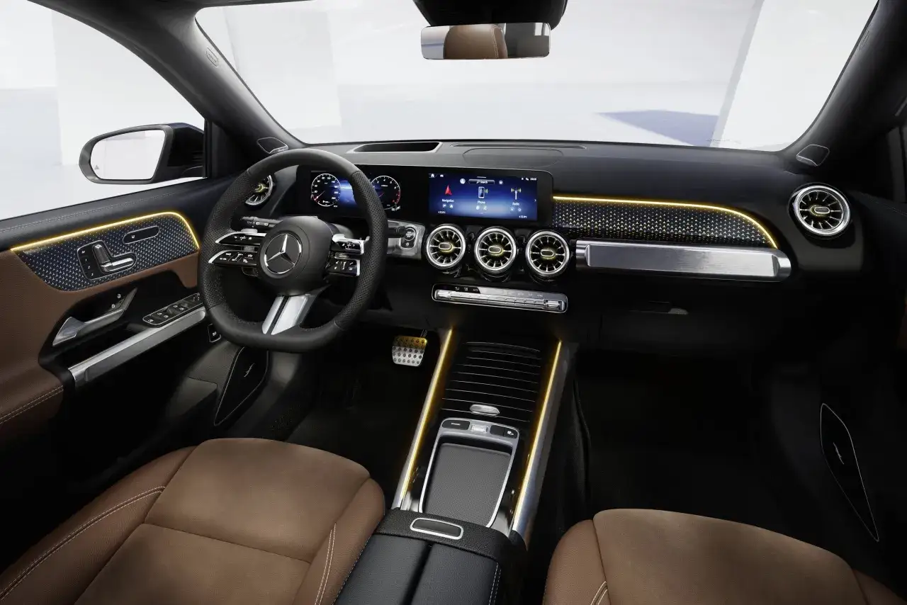 Wnętrze Mercedes GLB 200 z brązową tapicerką, nowoczesnym panelem i ambientowym oświetleniem.