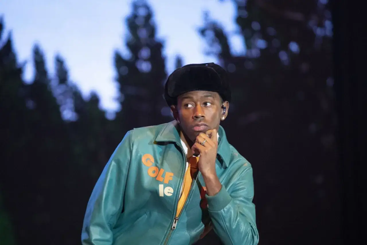 Tyler, The Creator w turkusowej kurtce z napisem