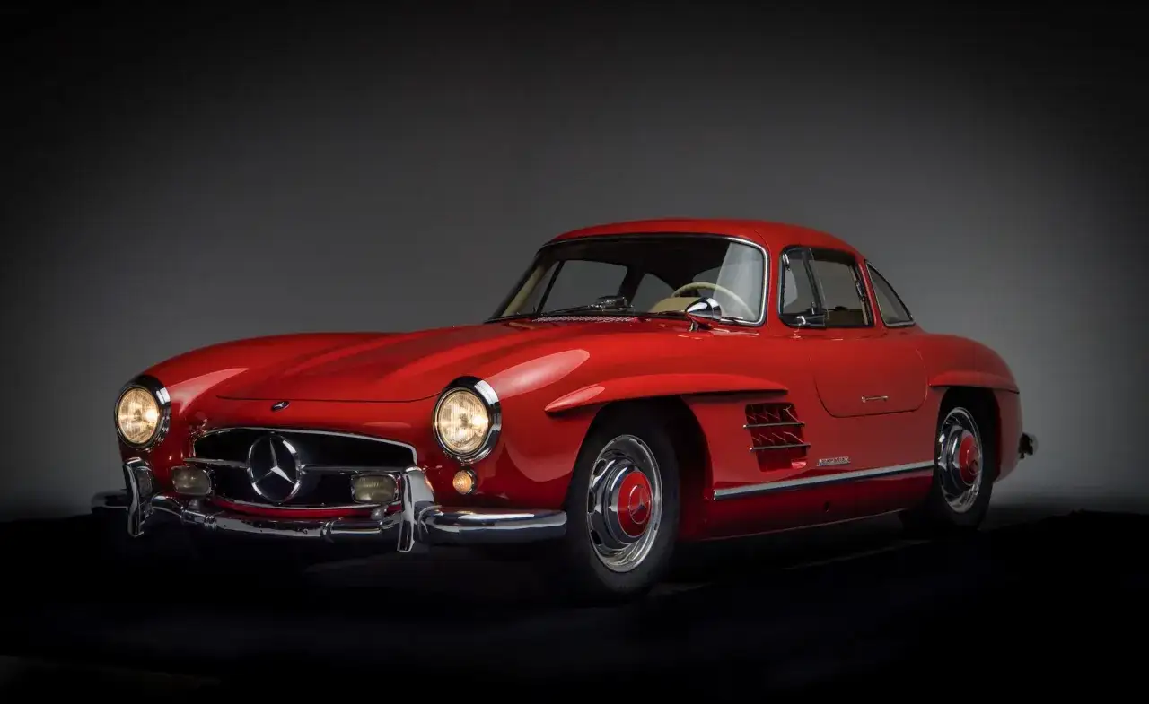 Czerwony Mercedes Gullwing, ikona motoryzacji, błyszczy w świetle reflektorów.