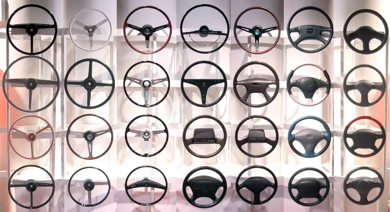 Exhibición de diversos tipos de volante, desde clásicos de tres radios hasta modernos con controles integrados.