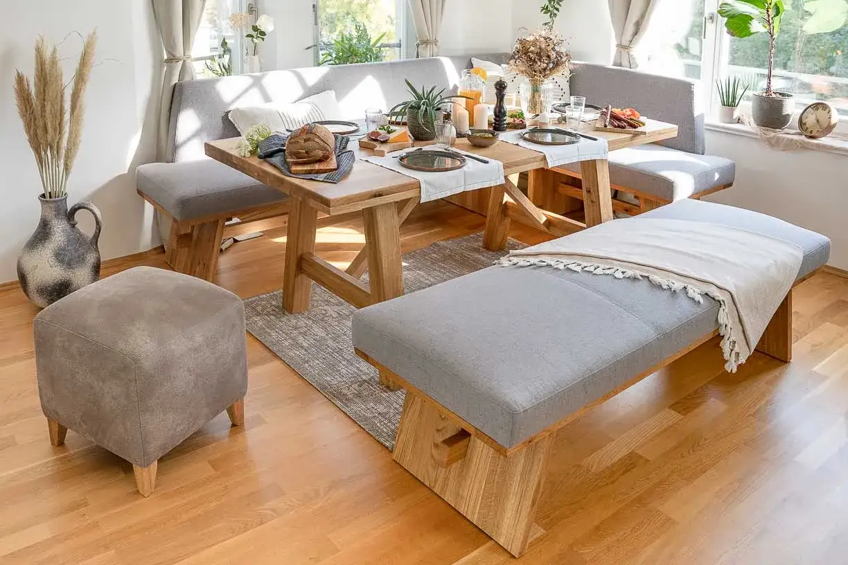 Gem&uuml;tliche Essecke modern gestalten mit Holztisch, grauer Eckbank und passendem Hocker. Einladend gedeckt f&uuml;r ein Fr&uuml;hst&uuml;ck.