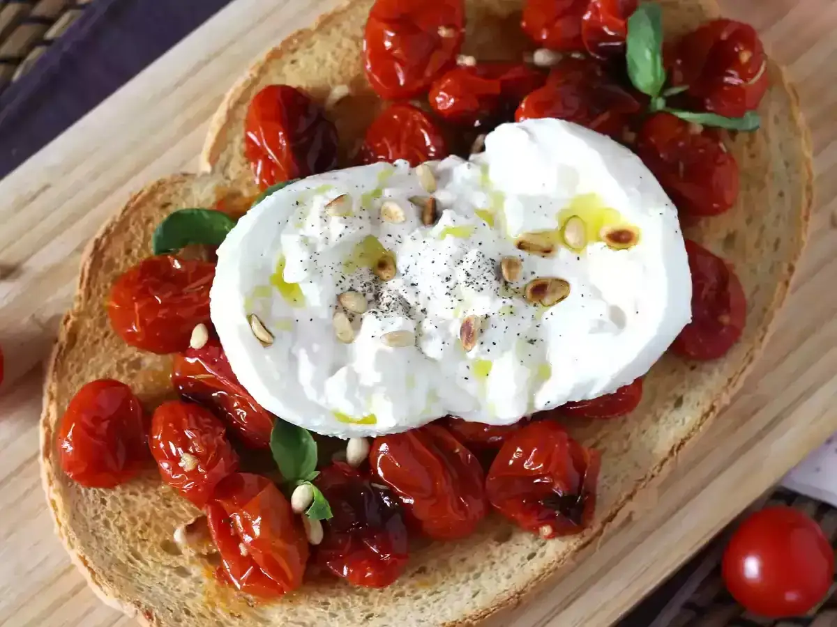 En härlig bruschetta med krämig burrata, rostade körsbärstomater, pinjenötter och basilika. En perfekt sommarrätt!