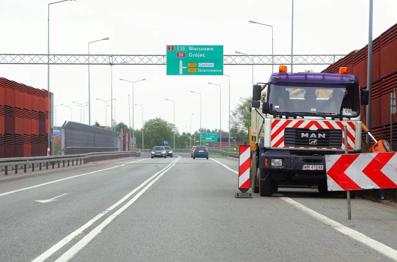 Ciężarówka blokuje drogę, sugerując, że wyprzedzanie na podwójnej ciągłej grozi mandatem.