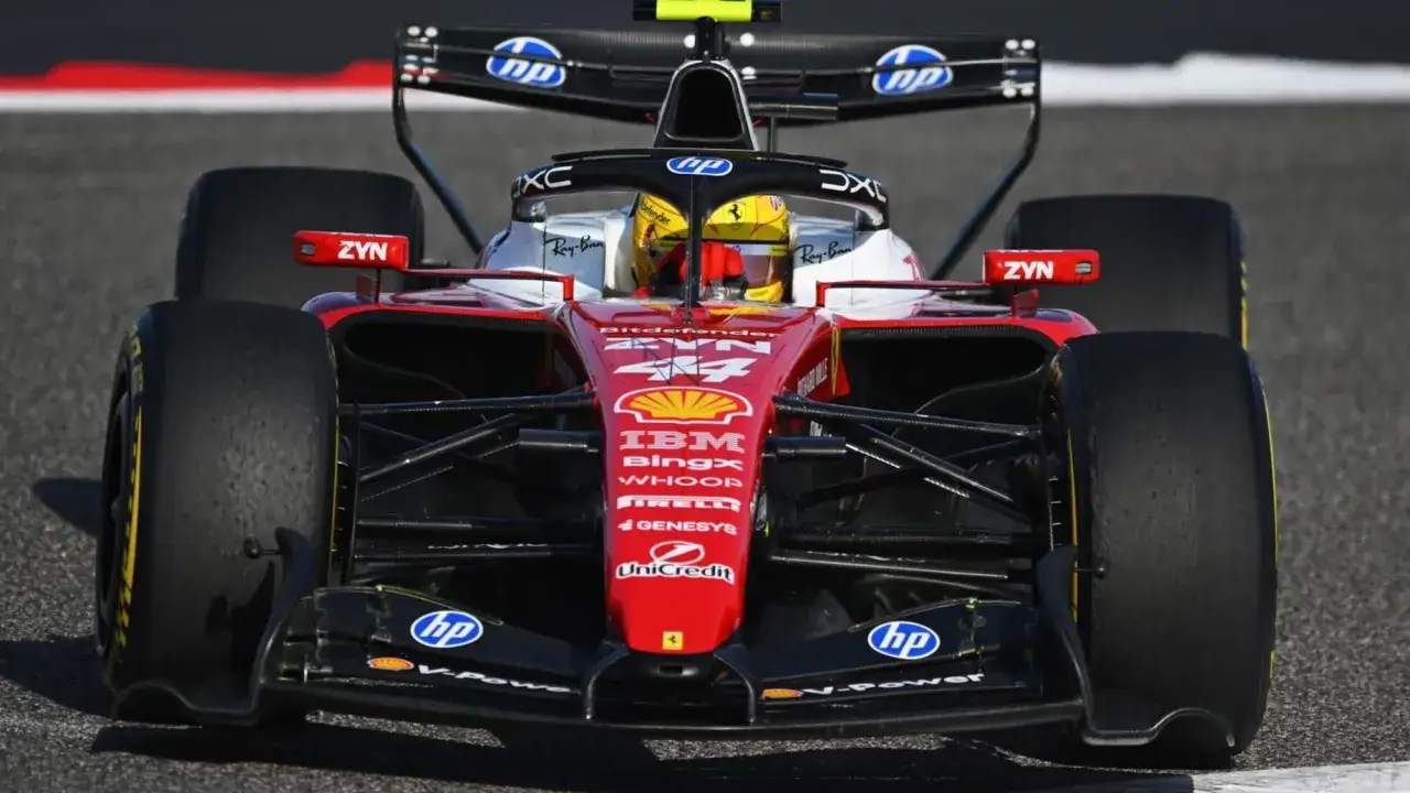 Il pilota con casco giallo guida una monoposto rossa di F1 in TV, con sponsor come IBM e Ray-Ban.