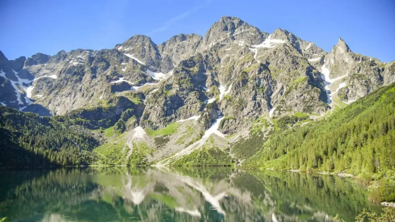 Górskie szczyty odbijają się w tafli jeziora, niczym świadkowie tego, jak powstało Morskie Oko.