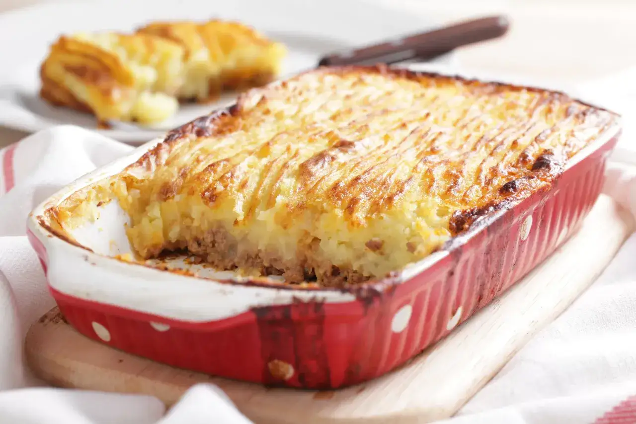 Un plat de hachis parmentier doré et gratiné, prêt à être dégusté. La purée de pommes de terre est joliment striée.