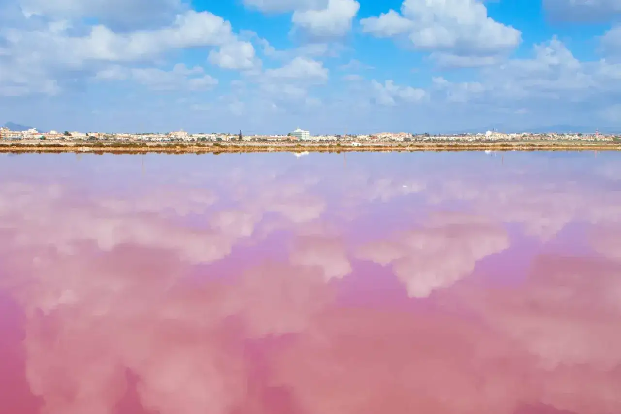 El reflejo de nubes blancas en el agua rosa de la playa rosa Murcia crea un paisaje surrealista.
